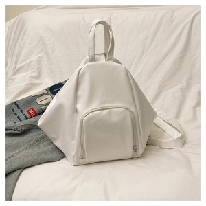 Detail of white geometric backpack with front zipper pocket and top handle on white fabric