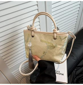 Close-up of elegant floral embroidery and tassel detail on a gold jacquard bucket bag