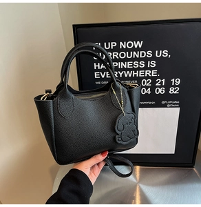 Détail du sac seau en cuir noir avec pendentif chien et garnitures dorées en métal