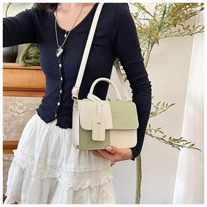 Detail of a chic cream and olive green crossbody bag with gold-tone buckle and handle