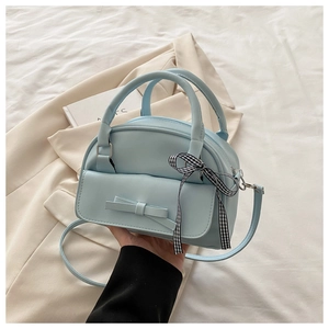 Detail view of light blue shell bag with decorative bow and checkered ribbon strap