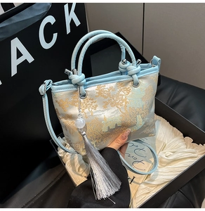 Detail of light blue silk embroidery bag featuring traditional Chinese motifs and tassels