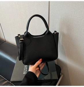 Détail du sac seau noir en cuir foulonné avec ferrures dorées et poignée