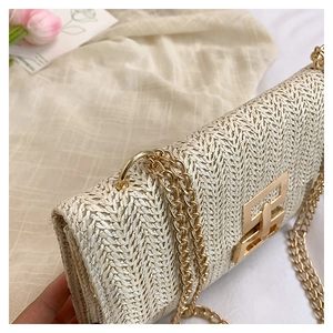 Detail of woven straw shoulder bag with gold chain strap and textured flap closure