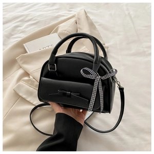Detail of black PU leather shell bag featuring a bow pocket and checkered ribbon handle