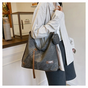 Detail of grey canvas hobo bag with brown leather trim and a matching round coin purse
