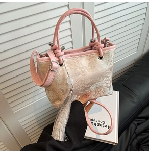 Detail view of pink and beige jacquard handbag with floral pattern and silver tassel