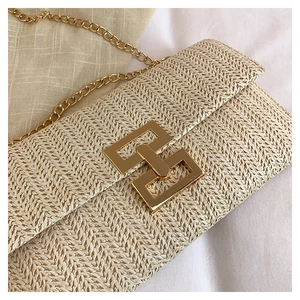 Macro detail of beige straw crossbody bag showing chic herringbone weave and gold clasp
