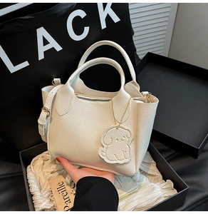 Détails de la texture en cuir grainé blanc et des ferrures dorées du sac à main chic