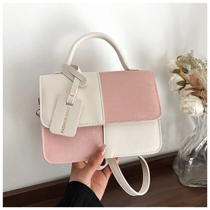 Pink and beige color-block crossbody bag with curved handle and gold-stamped tag detail
