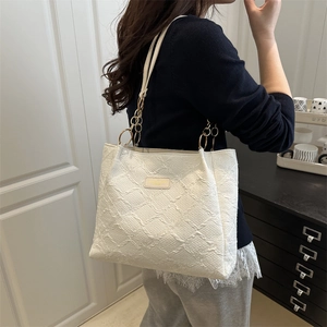 Sac cabas blanc minimaliste à texture gaufrée et chaîne dorée porté par un mannequin