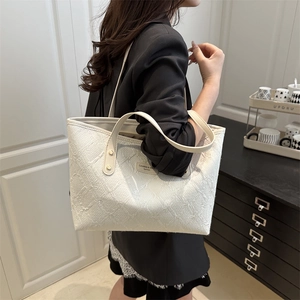 White quilted tote bag with textured fabric and beige handles shown on a model