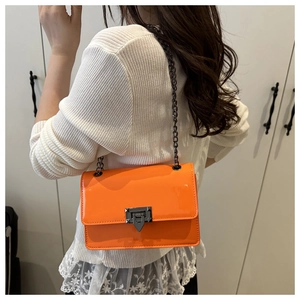 Modelansicht einer leuchtend orangen Umhängetasche mit Metallschnalle und Kettenriemen