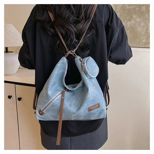 Blue soft fabric backpack with brown leather straps shown on a model in home setting