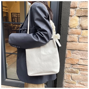 White textured leather tote bag detail with lace scarf accent and slim shoulder strap