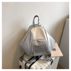 Detail of silver geometric backpack with metallic texture on a white suitcase