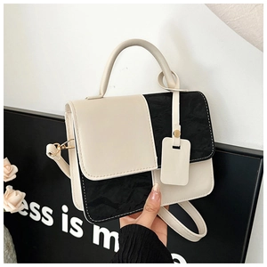 Detail view of contrast color shoulder bag with black and white stitching and strap