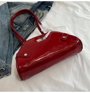 Close-up of glossy red bow handbag with white lace ribbon detail and metal zipper