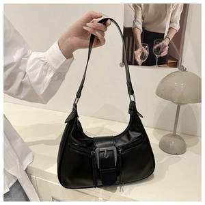 Detailed side view of a black Hobo shoulder bag with decorative metal buckle and long zippers