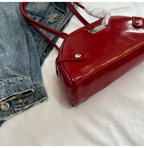 Detail of red patent leather shoulder bag with silver studs and white lace ribbon decoration