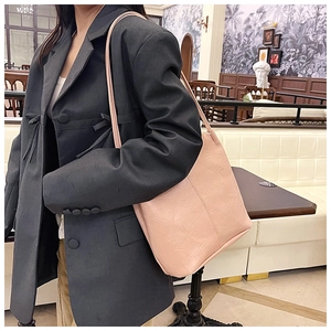 Detail of pink faux leather shoulder bag with floral embossing shown on a model