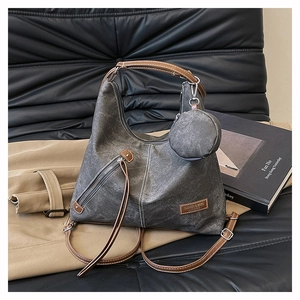 Detail of grey canvas hobo bag with brown leather handles and side zipper pocket