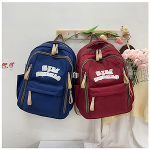 Dettaglio degli zaini in nylon blu e bordeaux con tasche a zip e scomparti laterali