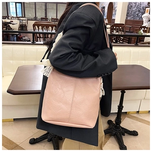 Close-up of pink tote bag with pleated texture on black blazer for office style