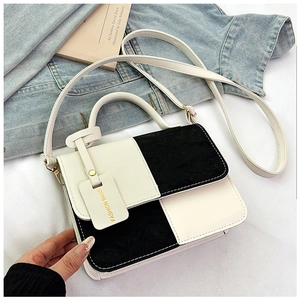 Detail of black and white contrast small square bag with decorative logo tag and golden hardware