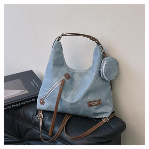 Detailed texture of blue vintage tote bag with leather strap and mini coin pouch accessory