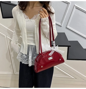 Detail of dark red shell bag with white lace bow and silver metal logo plate