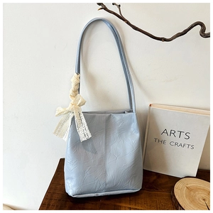 Detail of light blue bucket bag with pleated texture and creamy lace bow decoration