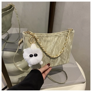 Detail of light green pleated shoulder bag with gold chain strap and plush monster charm