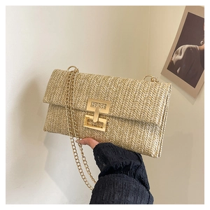 Detail of the woven texture and golden chain strap on a bohemian straw shoulder bag