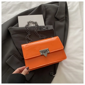 Detailansicht der orangefarbenen Lacklederhandtasche mit Metallschloss und Kettengurt