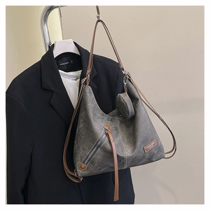 Detail of dark grey washed canvas hobo bag with brown leather strap and small round pouch