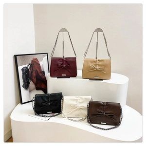 Bow accent crossbody bags in five colors with silver chain straps on white display