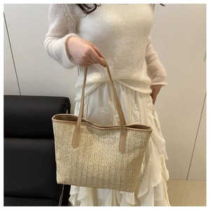 Détail d'un sac cabas en paille tressée avec chevrons et poignées en cuir marron