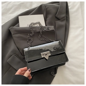 Details der glänzenden schwarzen Lackledertasche mit Silberkette und Schloss