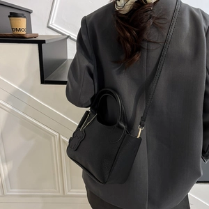 Sac seau chic en cuir grainé noir avec charme de chien sur escalier de style rue