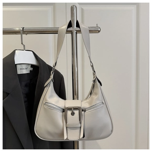 Close-up of cream leather crescent bag with metal buckle and symmetrical zippers