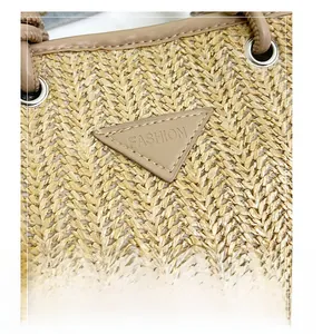 Detail of woven straw handbag featuring a triangle leather patch with FASHION engraving