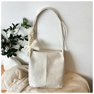 Detailed texture of beige shoulder bag with lace bow accessory and pleated leather finish