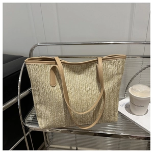 Détail du sac cabas en paille tressée à la main avec texture à chevrons et anse cuir
