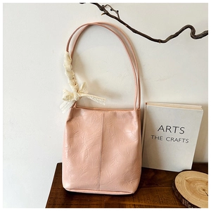 Pink pleated bucket bag with long shoulder strap and white lace bow charm detail
