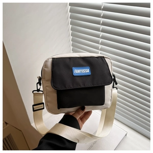 Detail of minimalist canvas crossbody bag featuring contrast stitching and wide strap