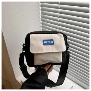 Detail of contrast color crossbody bag with silicone logo patch and adjustable strap