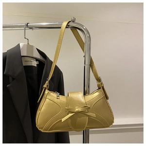 Détail d'un sac à bandoulière doré métallisé avec nœud décoratif et fermetures argentées