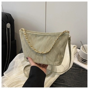 Detailed view of pale green ruched fabric texture and gold chain strap on handbag