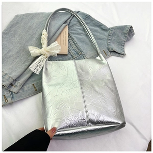 Detail of silver metallic tote bag featuring wrinkled leather and white lace bow accessory